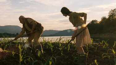 Szenenbild: Das Mädchen und sein Großvater bearbeiten den Maisacker