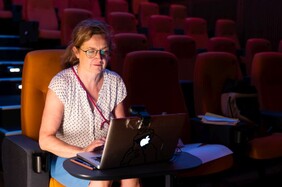 Sabine Genz auf einem Kinosessel hinter einem Laptop