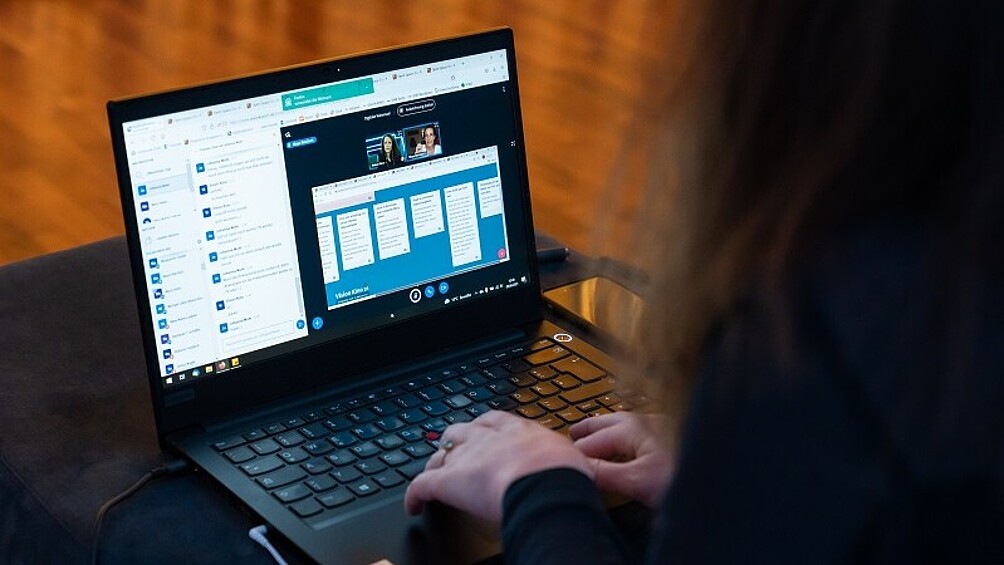 Blick auf einen geöffneten Laptop, der ein Videokonferenztool anzeigt
