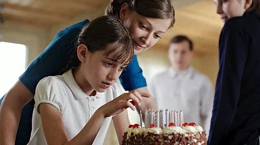 Szenenbild: Zwei Mädchen halten einen Kuchen in der Hand